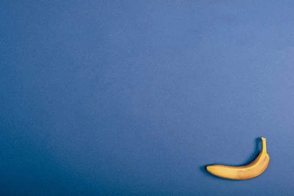 Вид зверху на стиглий і жовтий банан на синьому фоні з пробілом для копіювання — стокове фото