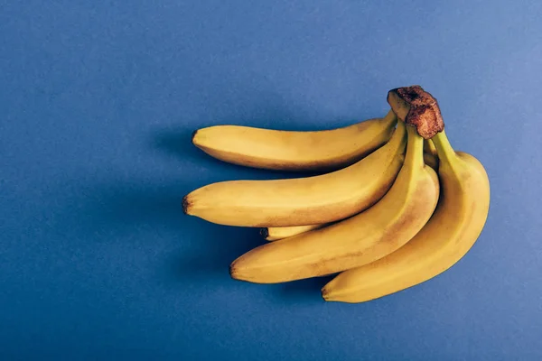 Vista dall'alto di gruppo maturo di deliziose banane su sfondo blu — Foto stock