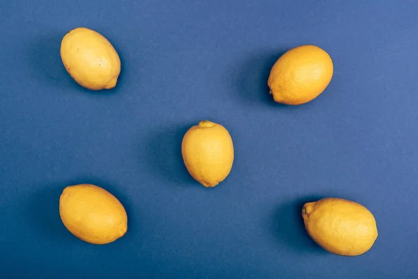 Вид зверху на свіжі яскраві та жовті лимони на синьому фоні — стокове фото
