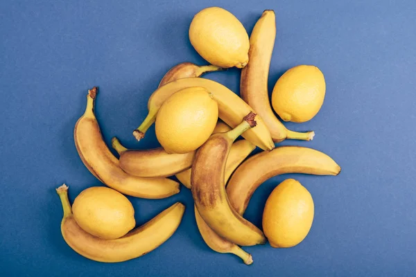 Top view of ripe and yellow bananas and lemons on blue background — Stock Photo