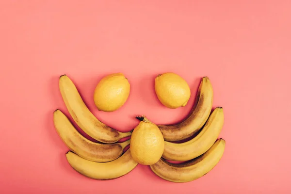 Flache Lage mit Essenszusammensetzung aus gelben saftigen Bananen und frischen Zitronen auf Korallenhintergrund — Stockfoto