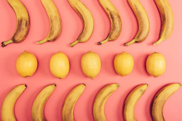 Верхний вид спелых желтых бананов и лимонов на коралловом фоне — стоковое фото