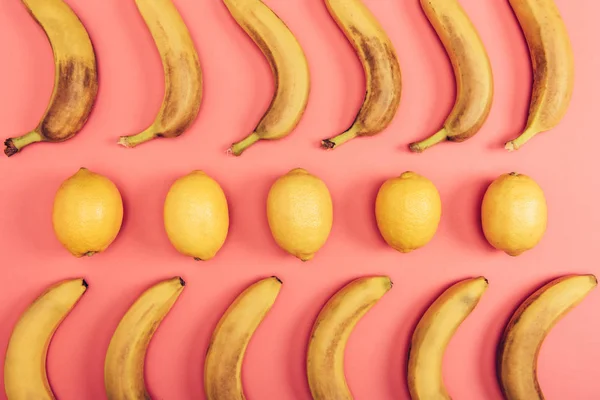 Vista dall'alto di banane gialle mature e limoni su sfondo corallo — Foto stock