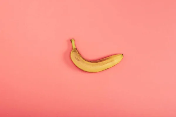 Vue de dessus de banane fraîche brillante et jaune sur fond de corail — Photo de stock