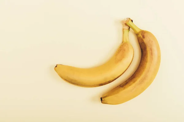 Вид зверху на смачні та жовті банани на світло-бежевому фоні — стокове фото