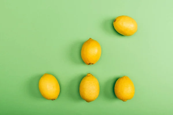 Vue de dessus des citrons frais et jaunes sur fond vert coloré — Photo de stock