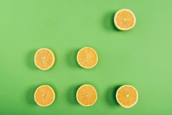 Vista superior de limones jugosos y amarillos sobre fondo verde colorido - foto de stock