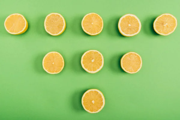 Blick von oben auf die Nahrungsmittelzusammensetzung aus saftigen und frisch geschnittenen Zitronen auf bunt grünem Hintergrund — Stockfoto