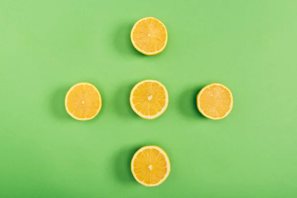 Top view of yellow and delicious cut lemons on colorful green background — Stock Photo