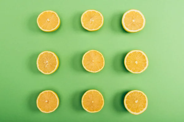 Top view of fresh and yellow cut lemons on colorful green background — Stock Photo