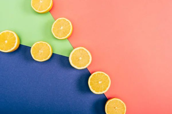 Vue de dessus des citrons coupés juteux, frais et jaunes sur fond multicolore — Photo de stock