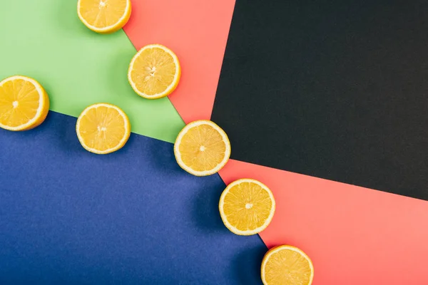 Top view of bright yellow cut lemons on multicolored blue coral green black background — Stock Photo