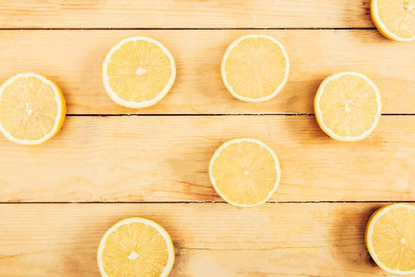 Draufsicht auf saftige, frische und gelb geschnittene Zitronen auf Holztischhintergrund — Stockfoto