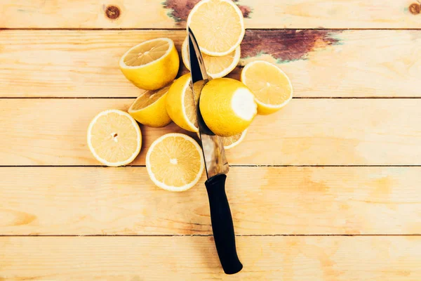 Vista dall'alto di limoni freschi e gialli con coltello su fondo tavolo in legno — Foto stock