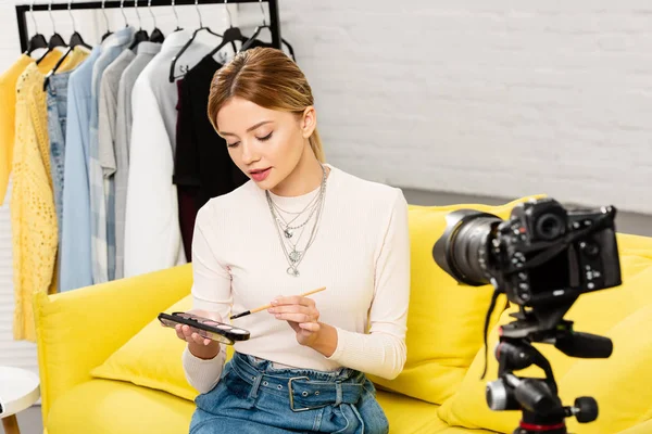 Belleza blogger haciendo maquillaje delante de la cámara de vídeo en casa - foto de stock