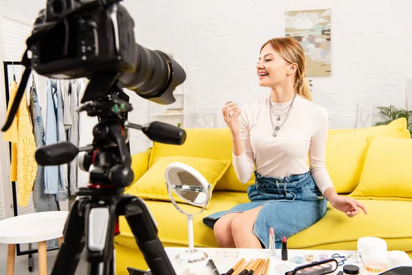 Sonriente blogger de belleza sosteniendo perfume delante de la cámara de video - foto de stock