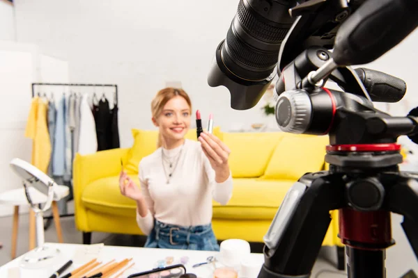 Foco seletivo do blogueiro de beleza segurando batons na frente da câmera de vídeo — Fotografia de Stock