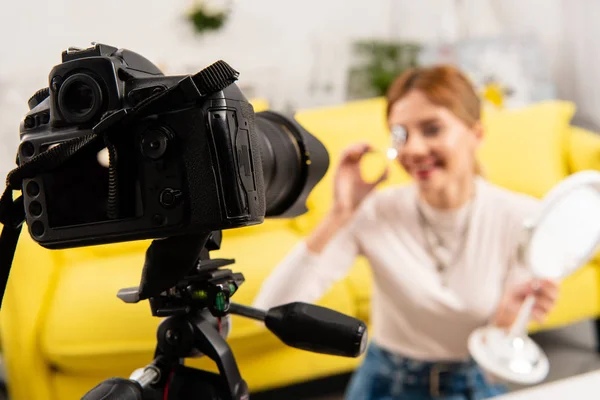 Selective focus of beauty blogger curling eyelashes in front of video camera — Stock Photo