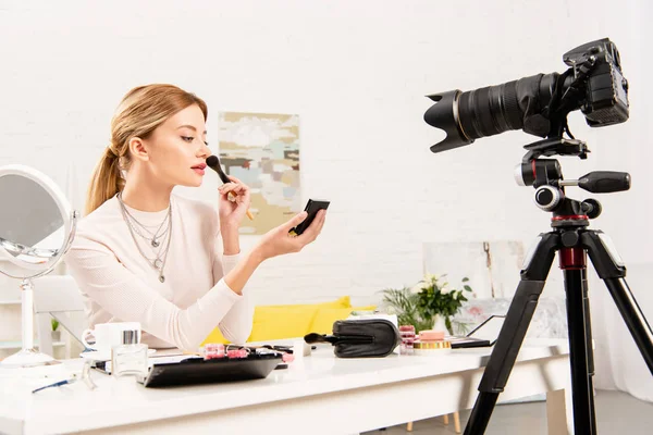 Belleza blogger aplicación de polvo facial delante de la cámara de vídeo - foto de stock