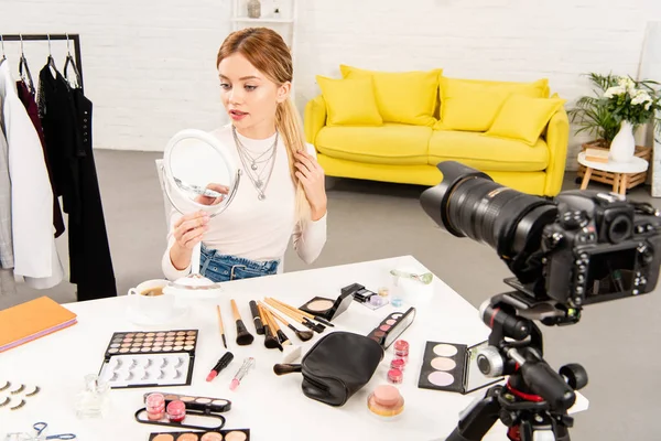 Belleza blogger mirando el espejo delante de la cámara de vídeo - foto de stock