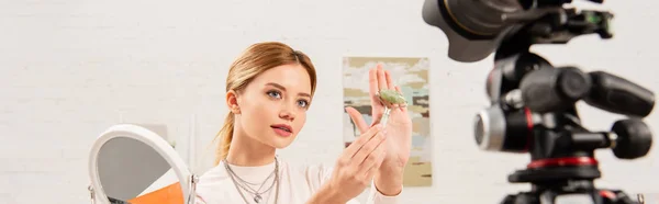 Panoramic shot of beauty blogger showing jade roller in front of video camera — Stock Photo