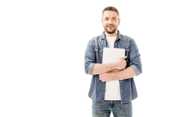 Вид спереди улыбающегося человека в джинсовой рубашке, держащего ноутбук изолированным на белом фоне — стоковое фото
