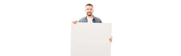 Tiro panorâmico de homem barbudo sorridente segurando cartaz em branco isolado em branco — Fotografia de Stock