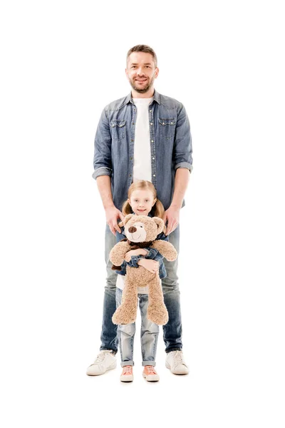 Visão de comprimento total do pai sorridente em jeans e filha com ursinho isolado em branco — Fotografia de Stock