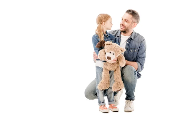 Lächelnder Vater und Tochter mit Teddybär, die sich isoliert auf weiß anschauen — Stockfoto