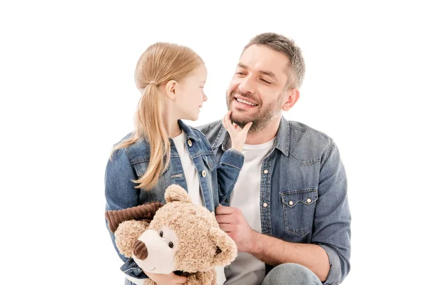 Sonrientes papá e hija con osito de peluche mirándose aislados en blanco - foto de stock