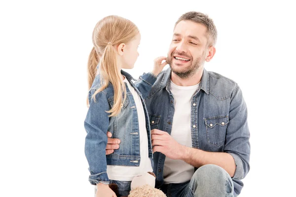 Padre sonriente en jeans e hija mirándose aislados en blanco - foto de stock