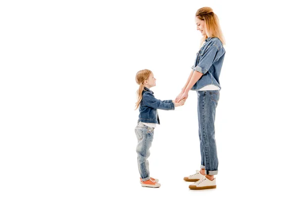 Side view of smiling mother and daughter holding hands and looking at each other isolated on white — Stock Photo