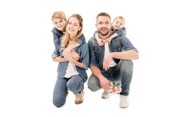 Familia feliz en jeans abrazando y sonriendo aislado en blanco - foto de stock