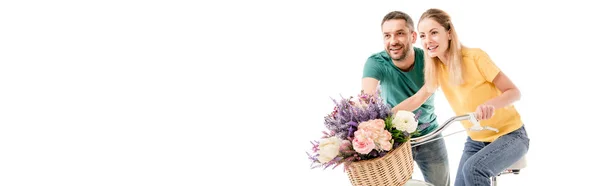 Plano panorámico de feliz pareja con bicicleta y cesta de flores aisladas en blanco - foto de stock
