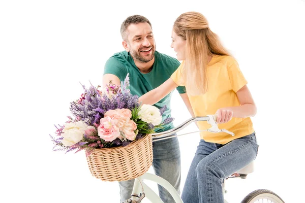 Glückliches Paar mit Fahrrad und Blumenkorb, die einander isoliert auf weißem Grund anschauen — Stockfoto