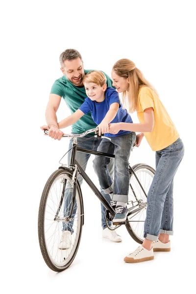 Full length view of smiling parents teaching son to ride bike isolated on white — Stock Photo