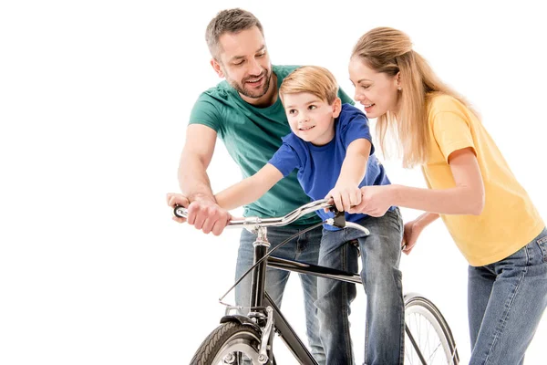 Padres sonrientes enseñando a su hijo a andar en bicicleta aislado en blanco - foto de stock