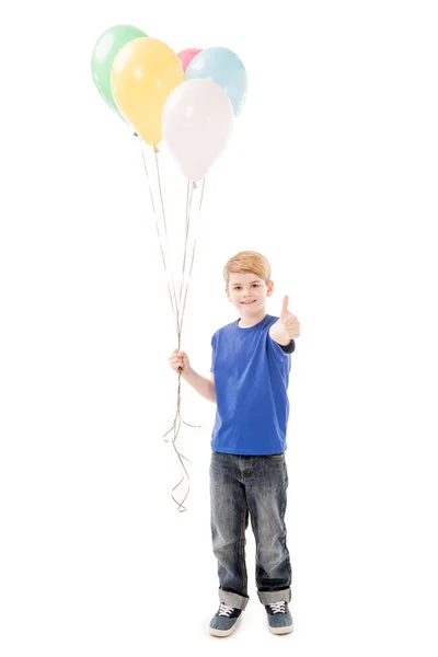 Повний вигляд усміхненої дитини, що тримає барвисті кульки і показує великий палець вгору ізольовано на білому — стокове фото