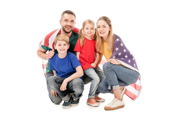 Lächelnde Familie mit amerikanischer Flagge, die isoliert auf weiß in die Kamera blickt — Stockfoto