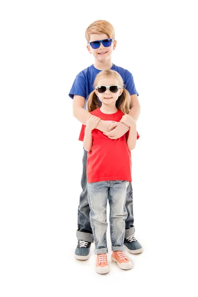 Full length view of sister and brother in sunglasses embracing isolated on white — Stock Photo