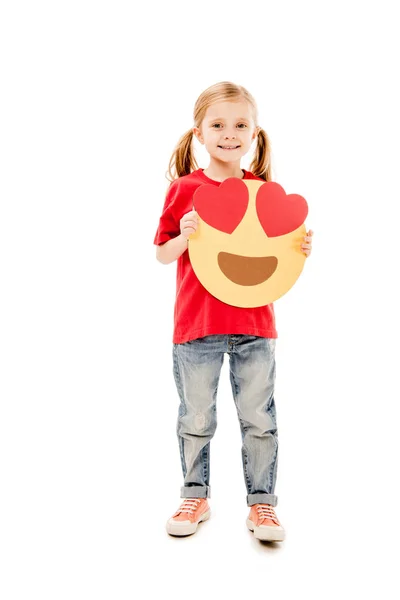 KYIV, UKRAINE - DECEMBER 20, 2019: full length view of smiling child holding smiley with heart eyes isolated on white — Stock Photo