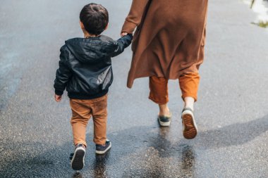 Bir kadının el ele tutuşması ve oğluyla yürümesi.