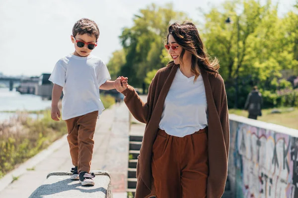 Snygg Mor Och Son Solglasögon Hålla Händer Medan Går Utanför — Stockfoto