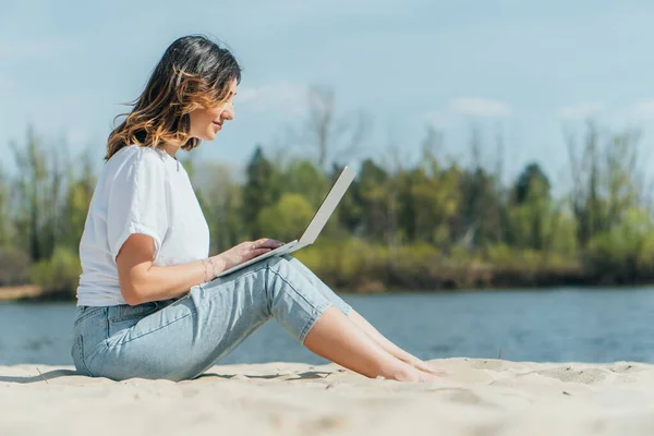 Вид Сбоку Счастливого Фрилансера Сидящего Песке Использующего Ноутбук — стоковое фото