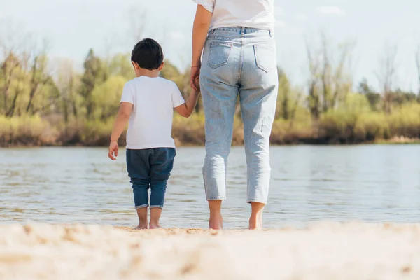 stock image back view of mother and son standing near river