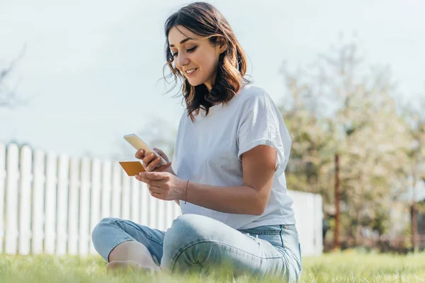 Selective Focus Happy Woman Sitting Grass Holding Credit Card Smartphone Stock Image