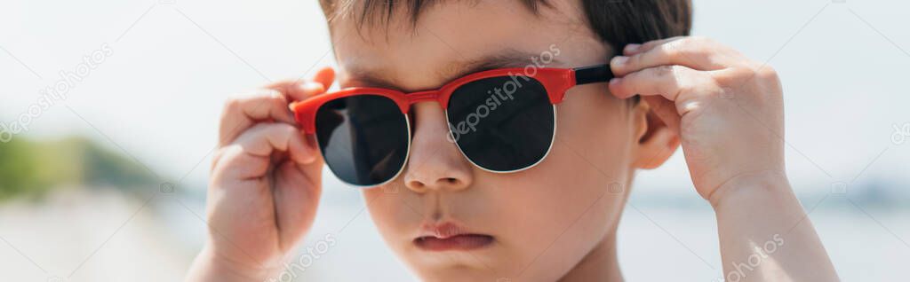 panoramic shot of cute and serious boy wearing stylish sunglasses 