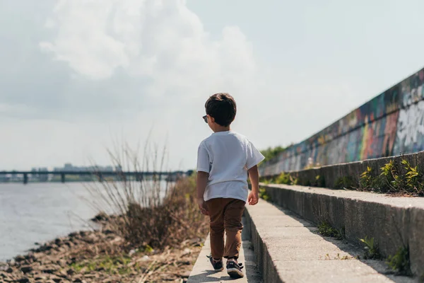 Vue arrière du garçon mignon marchant près de la rivière — Photo de stock