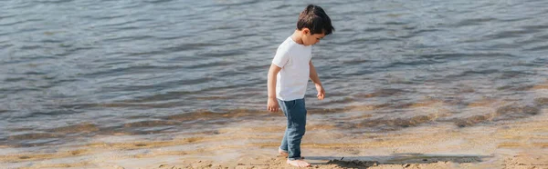 Панорамная ориентация симпатичного мальчика в джинсах в джинсах, стоящих у озера — стоковое фото