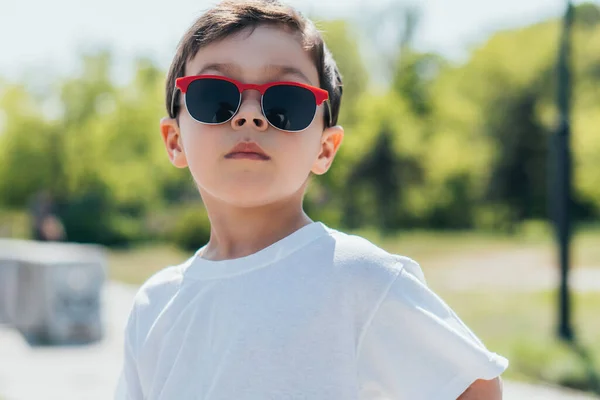 Élégant enfant dans des lunettes de soleil regardant la caméra — Photo de stock